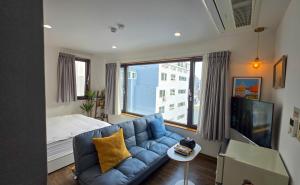 a living room with a blue couch and a large window at CatNap Guesthouse in Busan