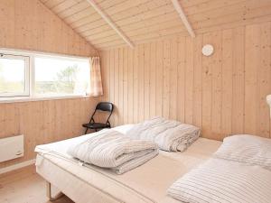 two beds in a room with wooden walls and a window at 5 star holiday home in Vestervig in Vestervig
