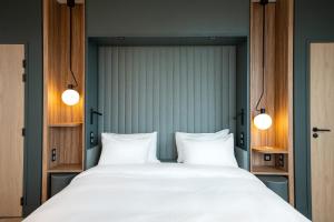 ein Schlafzimmer mit einem großen Bett und zwei weißen Kissen in der Unterkunft Radisson Hotel Reims in Reims