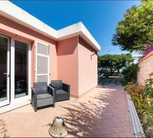 Dos sillas colocadas al costado de una casa. en La Casetta rosa, en Diano Marina