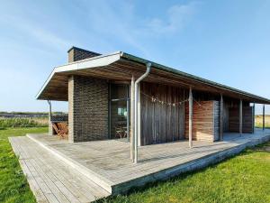 a house with a wooden deck in a field at 8 person holiday home in Vestervig-By Traum in Vestervig