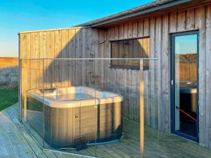 a bath tub on a deck with a glass wall at 8 person holiday home in Vestervig-By Traum in Vestervig