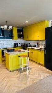 a kitchen with yellow cabinets and a stool in it at Retro House by the Sea in Hollington