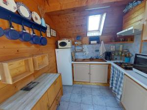a small kitchen with a white refrigerator and a sink at La Petite Maison en bois climatisée sud de Sarlat in Vézac