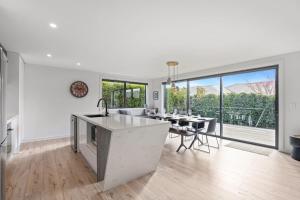 a kitchen and dining room with white walls and floor to ceiling windows at Getaway on Galloway - Close to the Lake in Wanaka