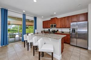 a kitchen with wooden cabinets and a bar with white chairs at Luxury Home With Private Pool And Water Park & Resort Access Near Disney At Encore Resorts Reunion - 240Mn in Kissimmee