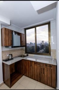 a kitchen with wooden cabinets and a large window at Queen Hotel in Addis Ababa