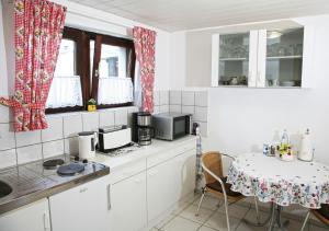 a kitchen with white cabinets and a table with a microwave at Ferienwohnung Christa Rohde in Bad Münder am Deister