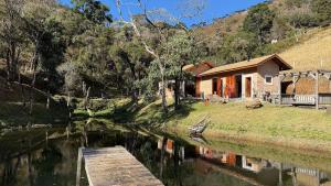 a cabin on the side of a river with a dock at Espetacular casa em Gonçalves - MG (2) in Gonçalves
