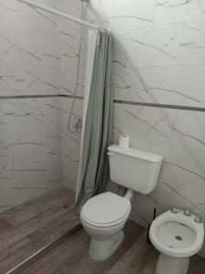 Un baño blanco con inodoro y ducha. en Departamentos DOÑA ELBA, en Río Colorado