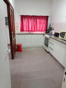 Una cocina con una ventana roja y una cortina roja. en Departamentos DOÑA ELBA, en Río Colorado