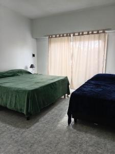 Un dormitorio con dos camas y una ventana. en Departamentos DOÑA ELBA, en Río Colorado