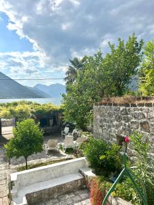 a garden with chairs and a stone wall and a lake at Mansarda apartment in Kotor