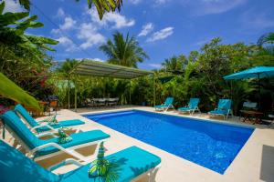 a pool with chairs and umbrellas at Casa Aloha on Los Mangos Street in Nosara