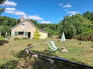 a yard with two lawn chairs and an umbrella at Gite la petite pataudiere in Le Guédéniau +12 photos