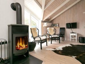 a fireplace in a living room with chairs and a table at 8 person holiday home in Ålbæk-By Traum in Ålbæk