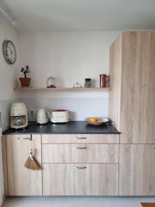 a kitchen with wooden cabinets and a clock on the wall at Appartement F3 Carolina - Triangle Annecy, Chamonix, Genève in Reignier +3 photos