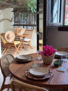 ein Holztisch mit Tellern, Gläsern und Blumen darauf in der Unterkunft Casa Buganvilla con piscina en San José Sotillo in San José