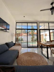 a living room with a couch and a table and windows at Villa Obo Pererenan by REJA Villas in Munggu