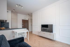 Una cocina y una sala de estar con un sofá y una mesa. en Bulwary nad Odrą Apartments z widokiem na rzekę Odrę i prywatnym miejscem parkingowym, en Szczecin