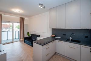 Una cocina con gabinetes blancos y una sala de estar. en Bulwary nad Odrą Apartments z widokiem na rzekę Odrę i prywatnym miejscem parkingowym, en Szczecin