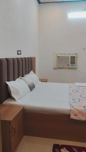 Una cama con sábanas blancas y almohadas en una habitación. en Ramansh Home stay, en Ayodhya