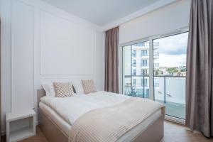 Un dormitorio con una cama y una ventana grande en Bulwary nad Odrą Apartments z widokiem na rzekę Odrę i prywatnym miejscem parkingowym, en Szczecin