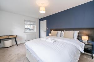 a bedroom with a large white bed with a blue wall at The Gordon Vacant Nests Heart Of Aberdeen in Aberdeen