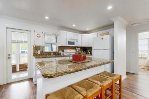 a kitchen with white cabinets and a counter with stools at Tobago Stars in Little Torch Key
