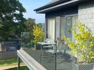 a glass balcony with a table and chairs on it at Estuary Watch in St Ives