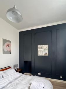 a bedroom with black walls and a white bed at Sea Spray Victorian Apartment in St. Leonards