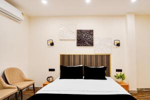 a bedroom with a large bed and two chairs at Hotel O Indriya in Noida