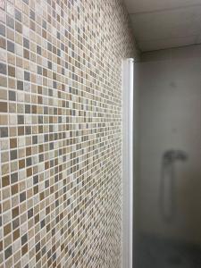 a bathroom with a shower and a tiled wall at Costa Sun Apartment in Calella