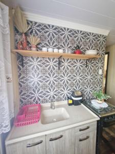 a kitchen with a sink and a patterned wall at Pousada Justi Oliveira in Louro Müller