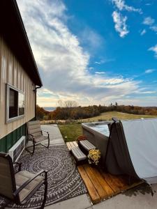 a deck with a tub and chairs on a house at Barn On The Ridge - HOT TUB - Sleeps 6 in De Soto