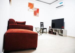 un soggiorno con sedia rossa e TV di Les muguets de chaville a Abidjan
