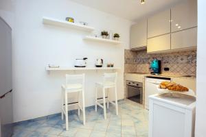 a kitchen with white cabinets and white stools at Dragone Hideaway in Ravello +3 photos