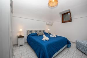 a bedroom with a blue bed with towels on it at Dragone Hideaway in Ravello