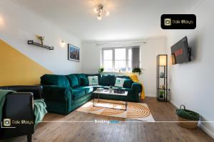 a living room with a green couch and a table at Quick Deals l 5 Bedroom l Sleeps 10 l Parking l Ideal for Groups l Oak Stays Short Lets & Serviced Accommodations in Churchdown