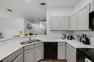 グランドプレーリーにあるTasteful 3BR I Free Parking I Workspaceの白いキャビネットとシンクのあるキッチン