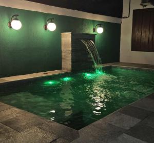 a swimming pool with a waterfall and green lights at Casa Galeria in Pirenópolis
