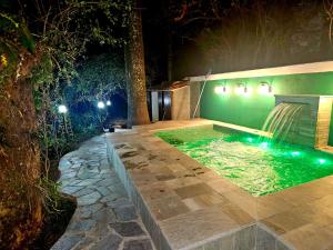 a swimming pool with a waterfall in a backyard at night at Casa Galeria in Pirenópolis +54 photos