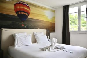 een hotelkamer met een bed met een schilderij van een heteluchtballon bij Best Western Hotel Ile de France in Château-Thierry