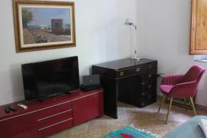 a living room with a flat screen tv and a dresser at A garden on the bay in Castiglioncello