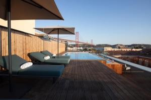 ein Balkon mit Stühlen und Sonnenschirm und ein Pool in der Unterkunft MACAM Hotel in Lissabon