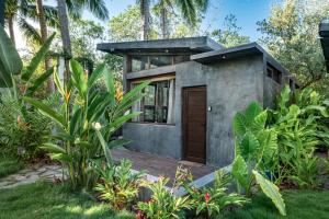 a small house with a wooden door in a garden at Riptide Lodge in El Paredón Buena Vista