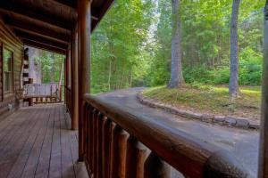 a porch of a log cabin with a bench on it at Rosey Bear cabin in Pittman Center