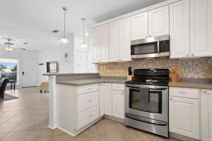 a kitchen with white cabinets and a stove top oven at Steps from the Sand and Town Green - 2BR Coastal Retreat in Long Beach +13 photos