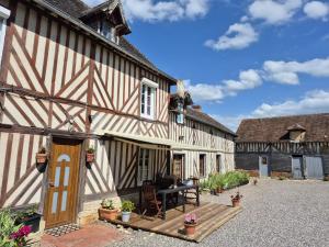 an old building with a wooden porch and a patio at Le Bois Rouland in Le Mesnil-Mauger