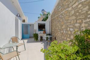 een terras met stoelen en een stenen muur bij Statis House in Lardos